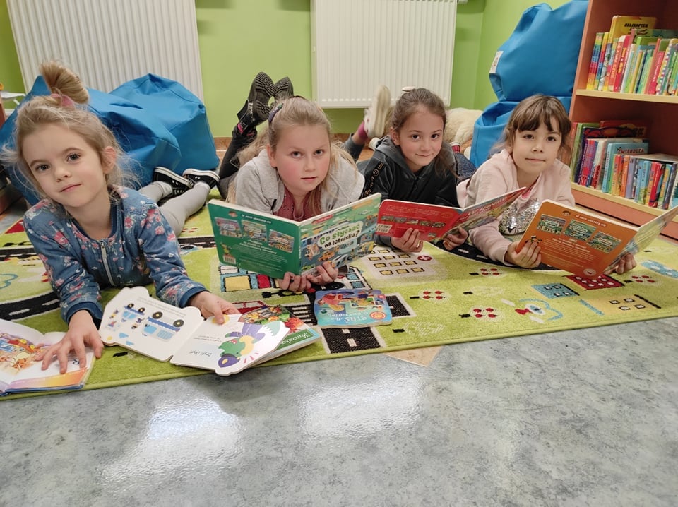 grupa dzieci na dywanie czytająca książki