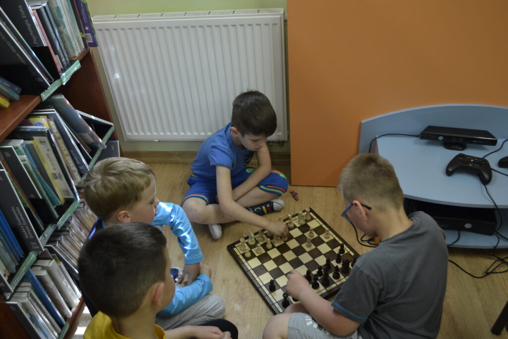dzieci grają w szachy w bibliotece