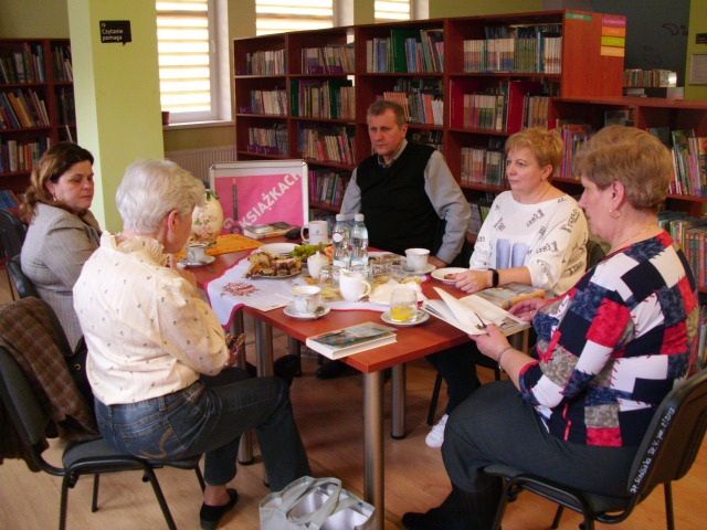 Grupa osób przy stole rozmawia o literaturze