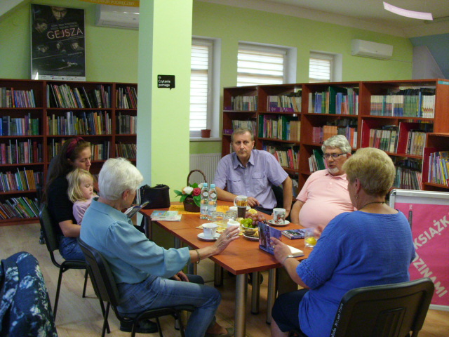 grupa osób przy stole w bibliotece