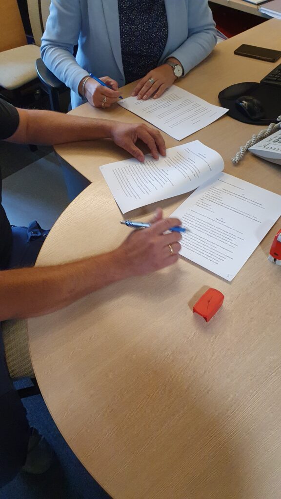 dwie osoby podpisują umowę w bibliotece