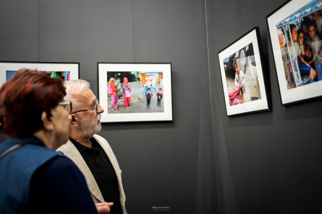 osoby oglądają fotografie na wystawie