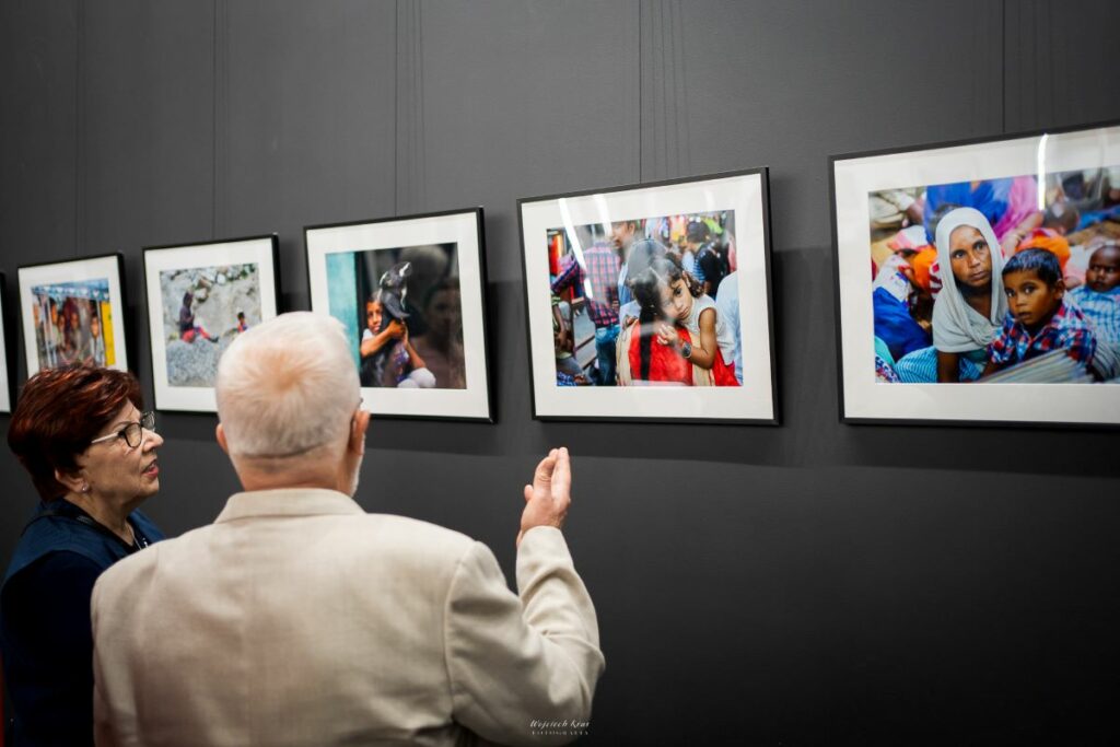 osoby oglądają fotografie na wystawie