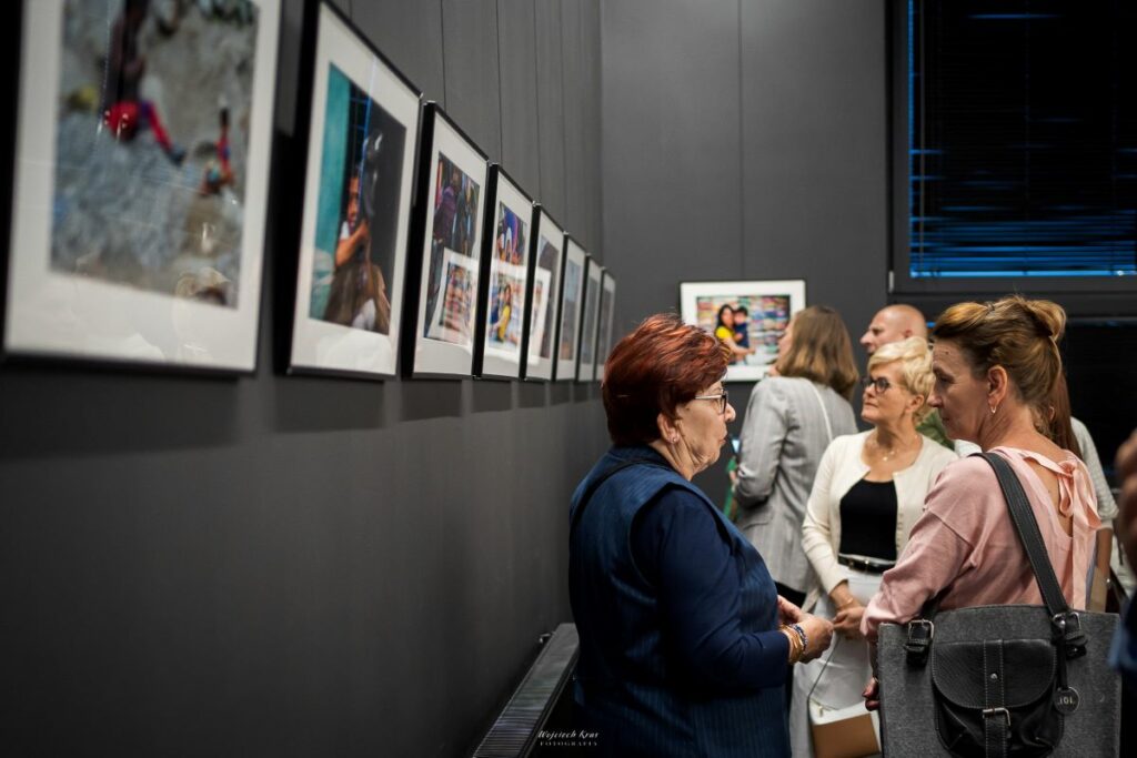 osoby oglądają fotografie na wystawie