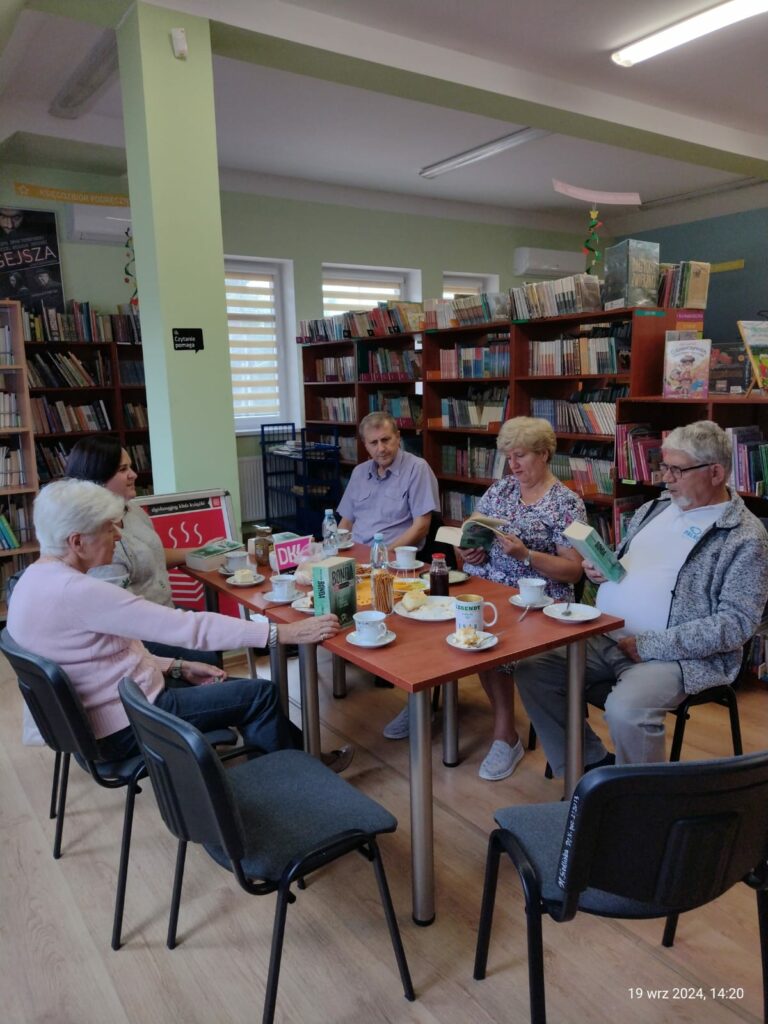 kilka osób przy stole w bibliotece rozmawia o ksiażkach