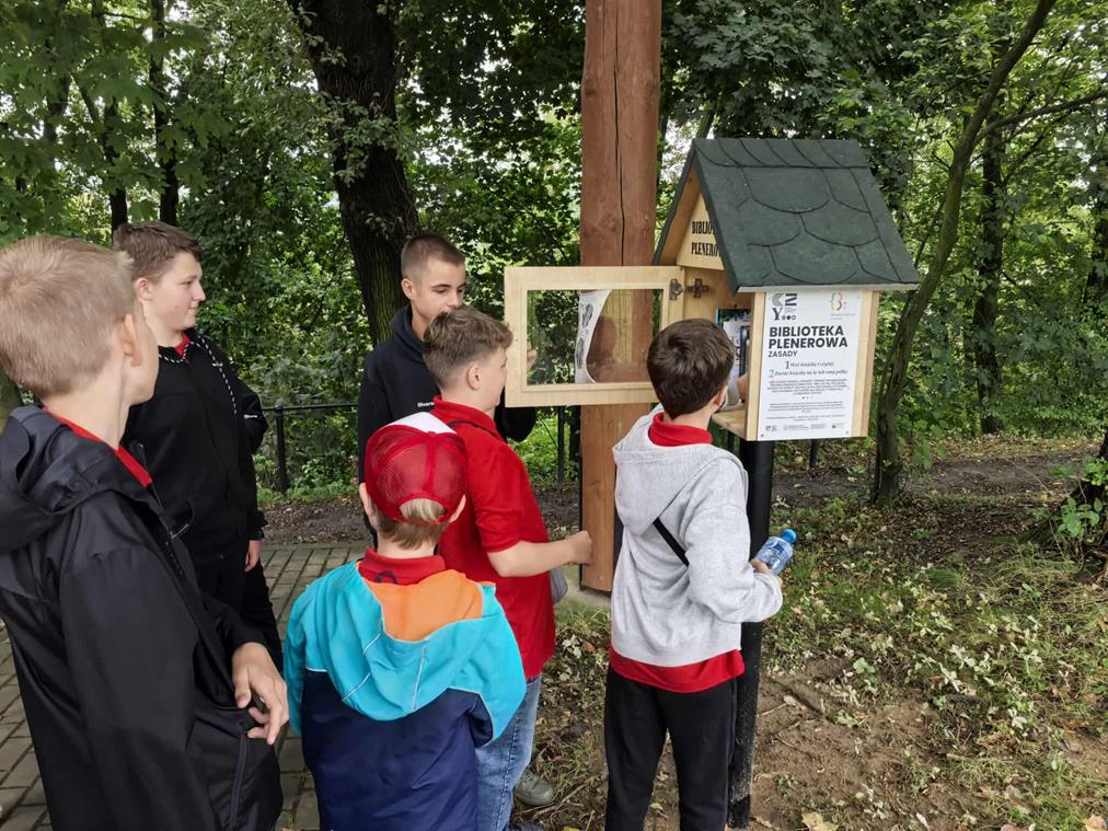 chłopiec wkłada książki do biblioteczki plenerowej