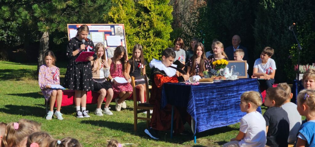 Grupa osób w plenerze podczas narodowego czytania