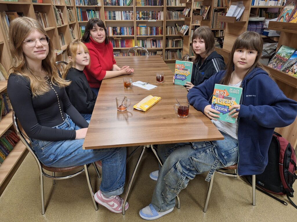 grupa osób przy stole w bibliotece