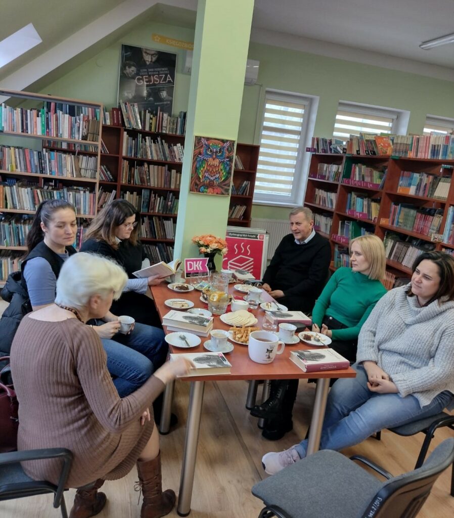 grupa osób przy stole z książkami w bibliotece