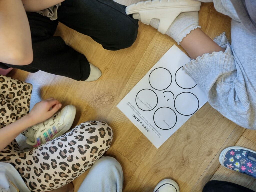 kartka papieru na stole a obok siedzące dzieci