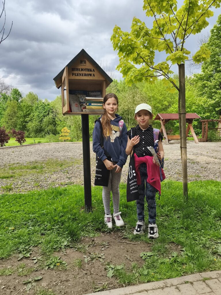 dwie osoby przed biblioteczką plenerową