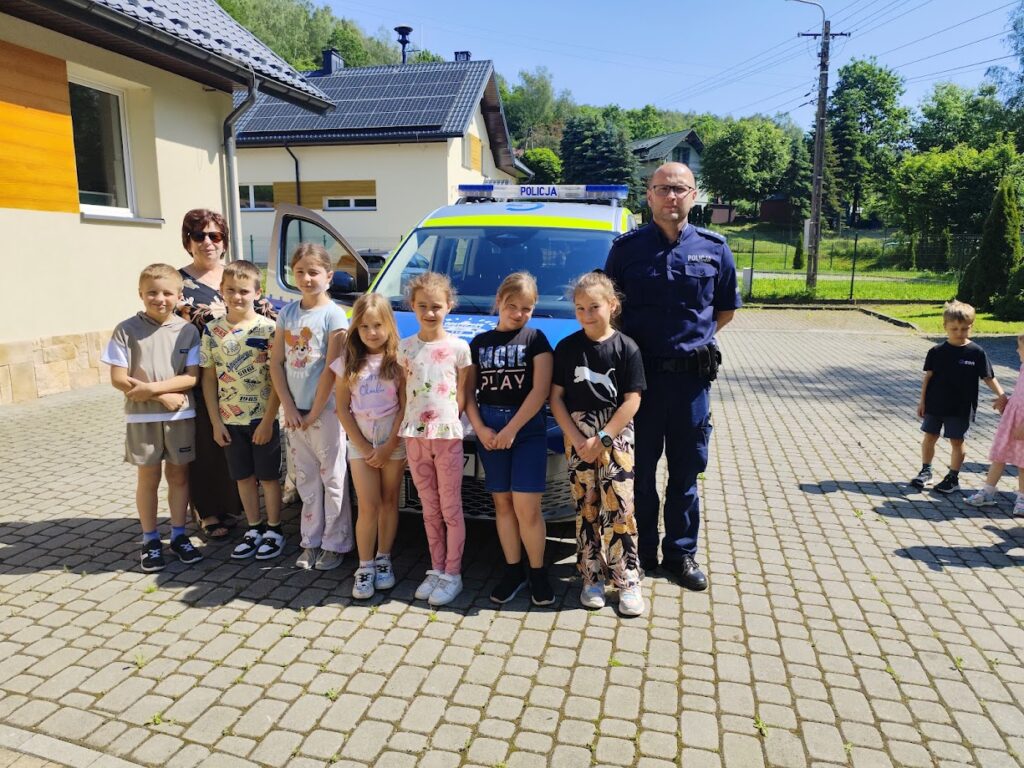 grupa dzieci z policjantem przed biblioteką