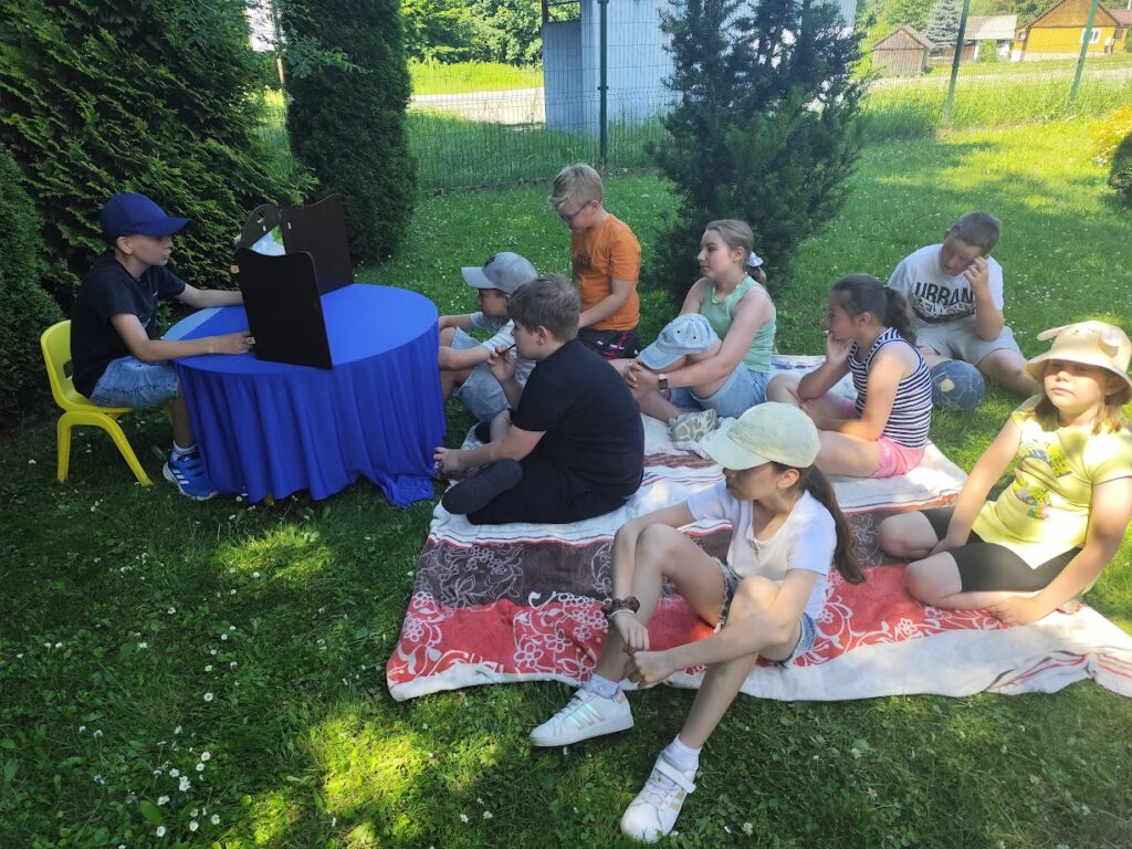 dzieci na kocyku słuchają głośnego czytania